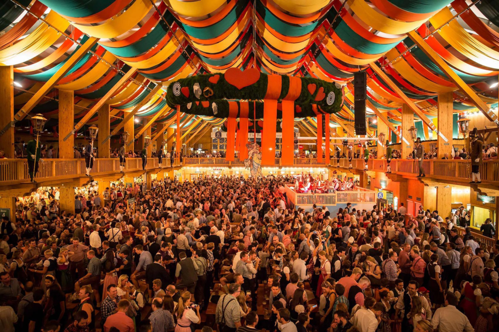 green yellow red decorated celling of Oktoberfst Hall full with many people