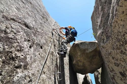 The big stone hang between two rock walls in Castellmezzano and  a man climbs on one of the rock walls 